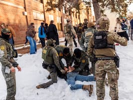 US federal immigration agents detain a person outside a school in Minneapolis during enforcement raids, January 2026. Photo by Kerem Yucel/AFP via Getty Images